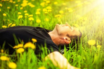 Junger Mann entspannt auf Blumenwiese