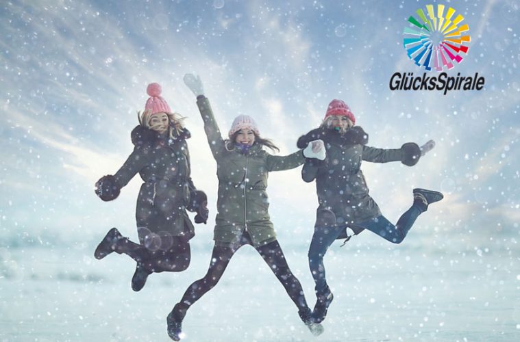 Drei junge Frauen springen im Schnee in die Höhe