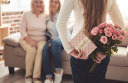 Tochter überrascht Mutter mit Blumenstrauß und Geschenk am Muttertag