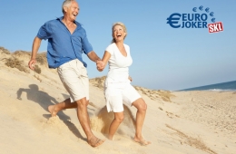 Glückliches Rentner-Paar läuft am Strand entlang