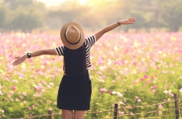 Junge Frau schaut auf Blumenwiese und genießt Freiheit