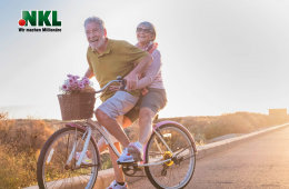 Älteres Ehepaar fährt im Sommer mit dem Fahrrad im Sonnenuntergang. Sie lachen und sind glücklich.