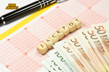 EuroJackpot geknackt! Würfel mit Buchstaben auf denen Jackpot steht liegen auf einem Spielschein mit Geld.